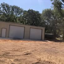There is a garage with two garage doors in the middle of a dirt field.