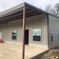 A metal building with a covered porch and windows.