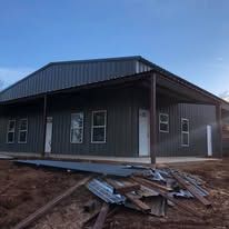 A metal building with a porch and a lot of windows is being built.