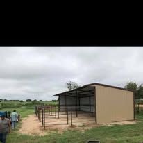 A group of people are standing in front of a shed in a field.