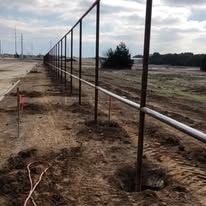 A fence is being built in the middle of a dirt field.