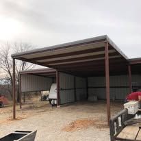 A covered carport with a trailer parked underneath it.