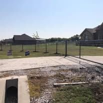 A fence is being built in a yard in front of a house.