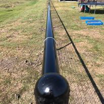 A black pole is sitting in the middle of a grassy field.