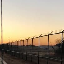 A fence surrounding a field with a sunset in the background.