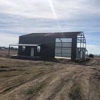 A large metal building is sitting in the middle of a dirt field.