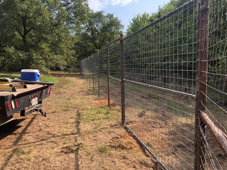 A trailer is parked next to a fence in a field.
