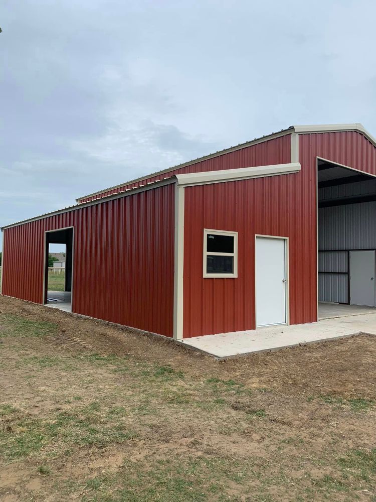 A red metal building with a white door and window is sitting in the middle of a field.