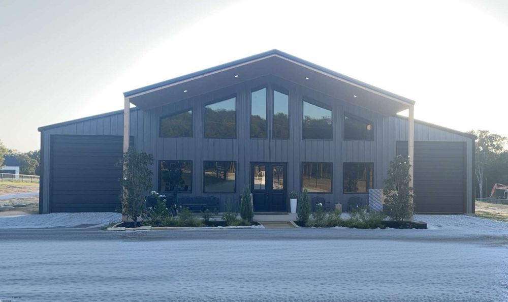 A large black building with a lot of windows is sitting in the middle of a parking lot.