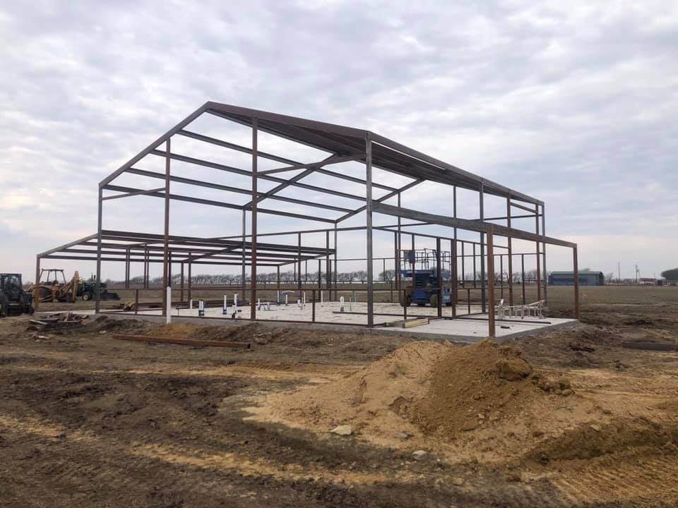 A large metal structure is being built in a dirt field.