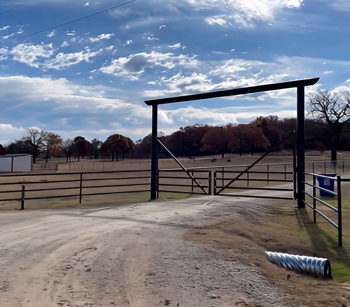 A dirt road with a fence and a gate that says g on it