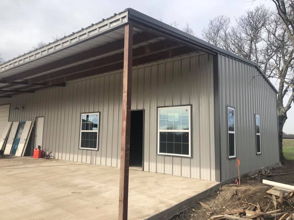 A metal building with a porch and windows is being built.
