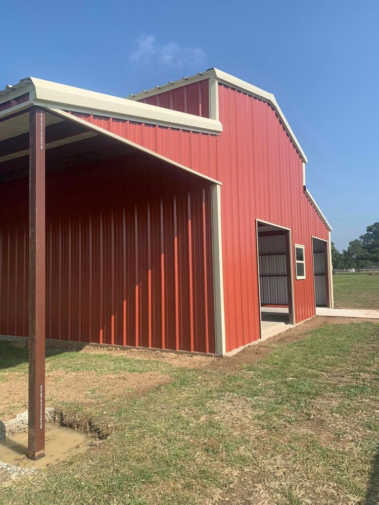 A red barn with a white roof is sitting in the middle of a grassy field.