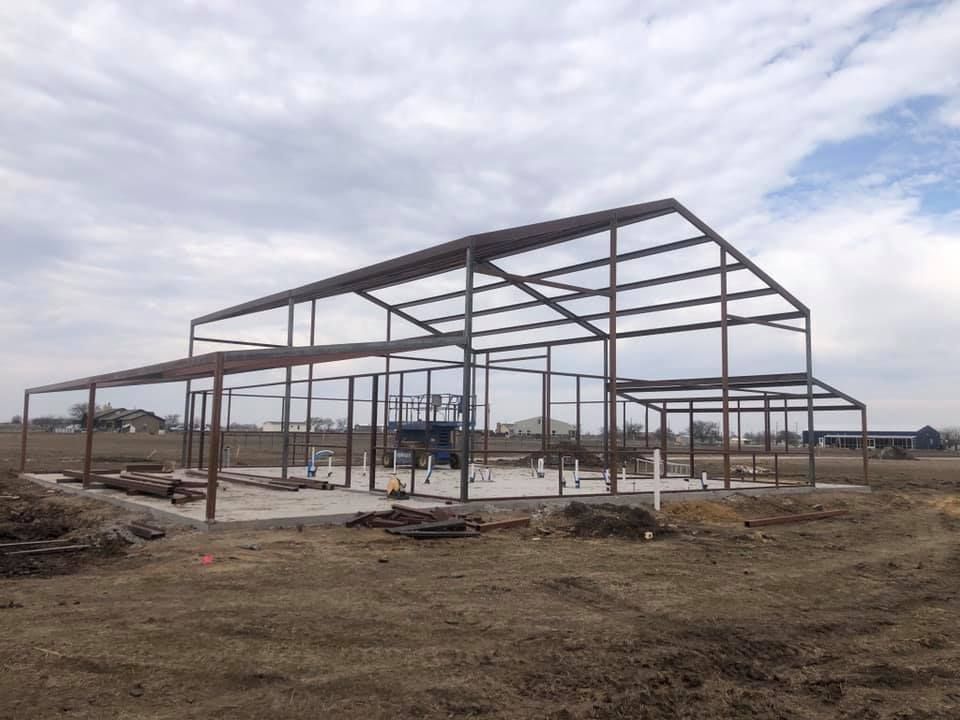 A large metal structure is being built in a field.
