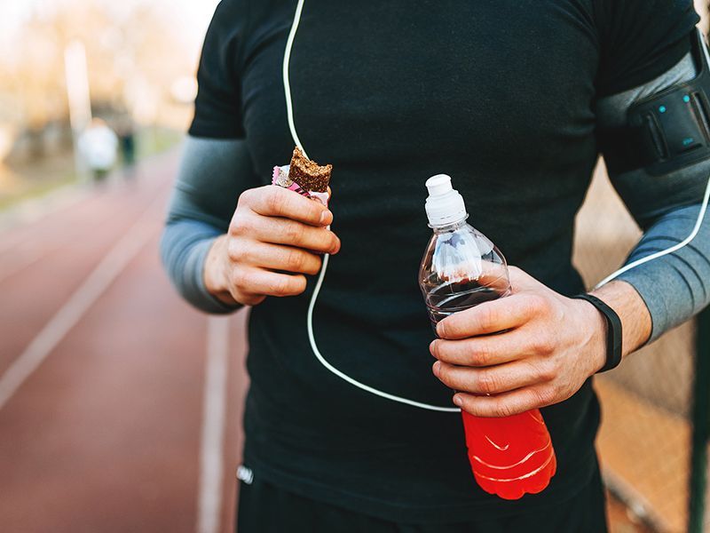 Un uomo tiene in mano una bottiglia d'acqua e uno snack.