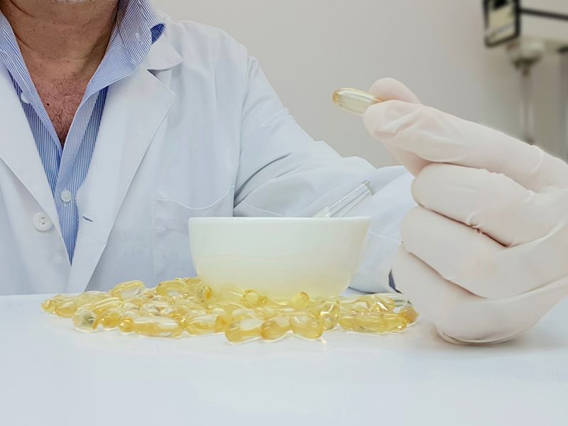 Un medico tiene in mano una capsula sopra una ciotola di pillole.