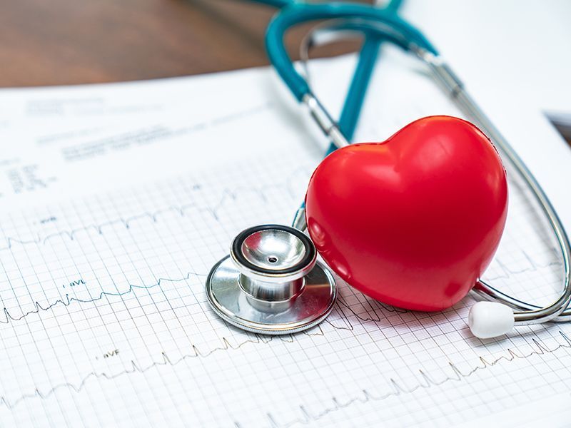 Un cuore rosso è appoggiato su uno stetoscopio su un grafico del battito cardiaco.