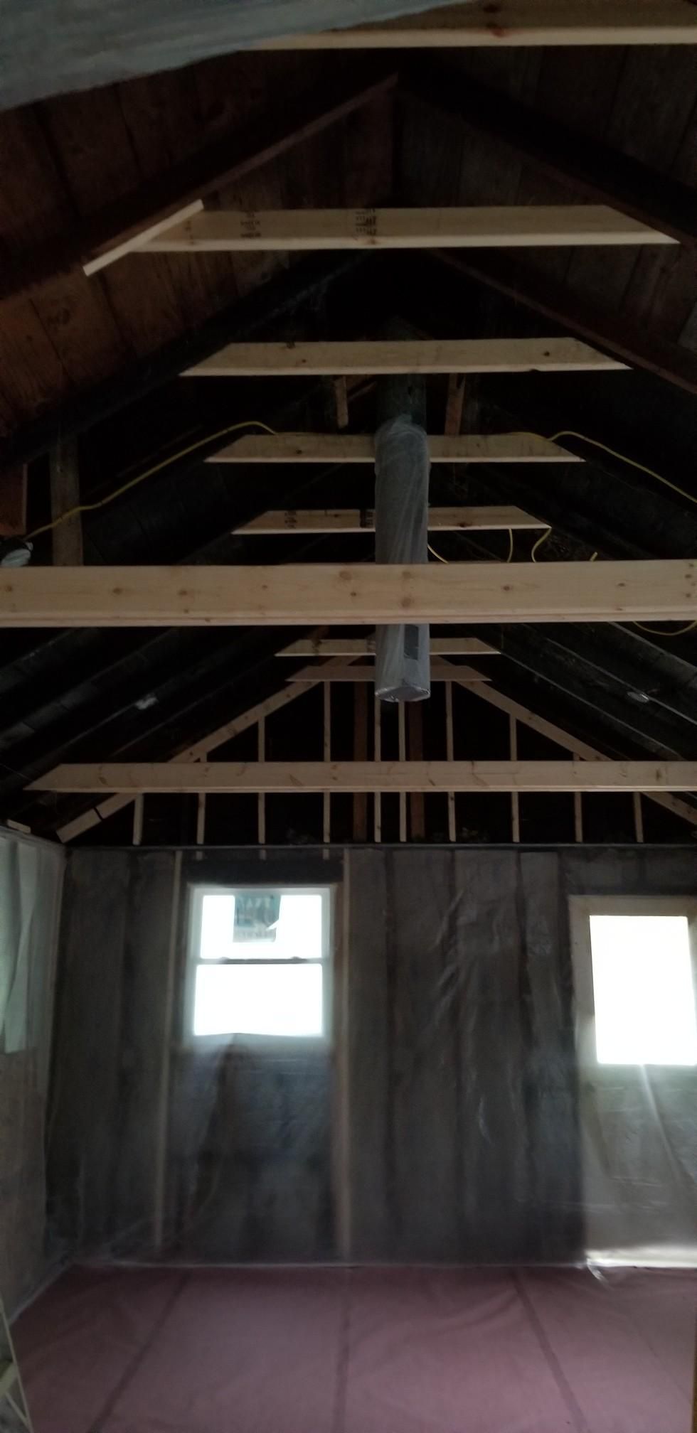 A room with a ceiling that is being built and a window.
