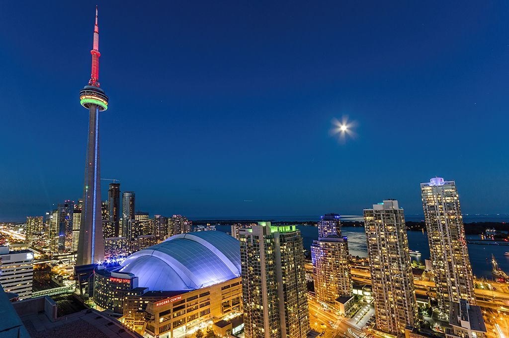 Toronto skyline at night with city lights and CN Tower, photographed from a rooftop using auto mode.
