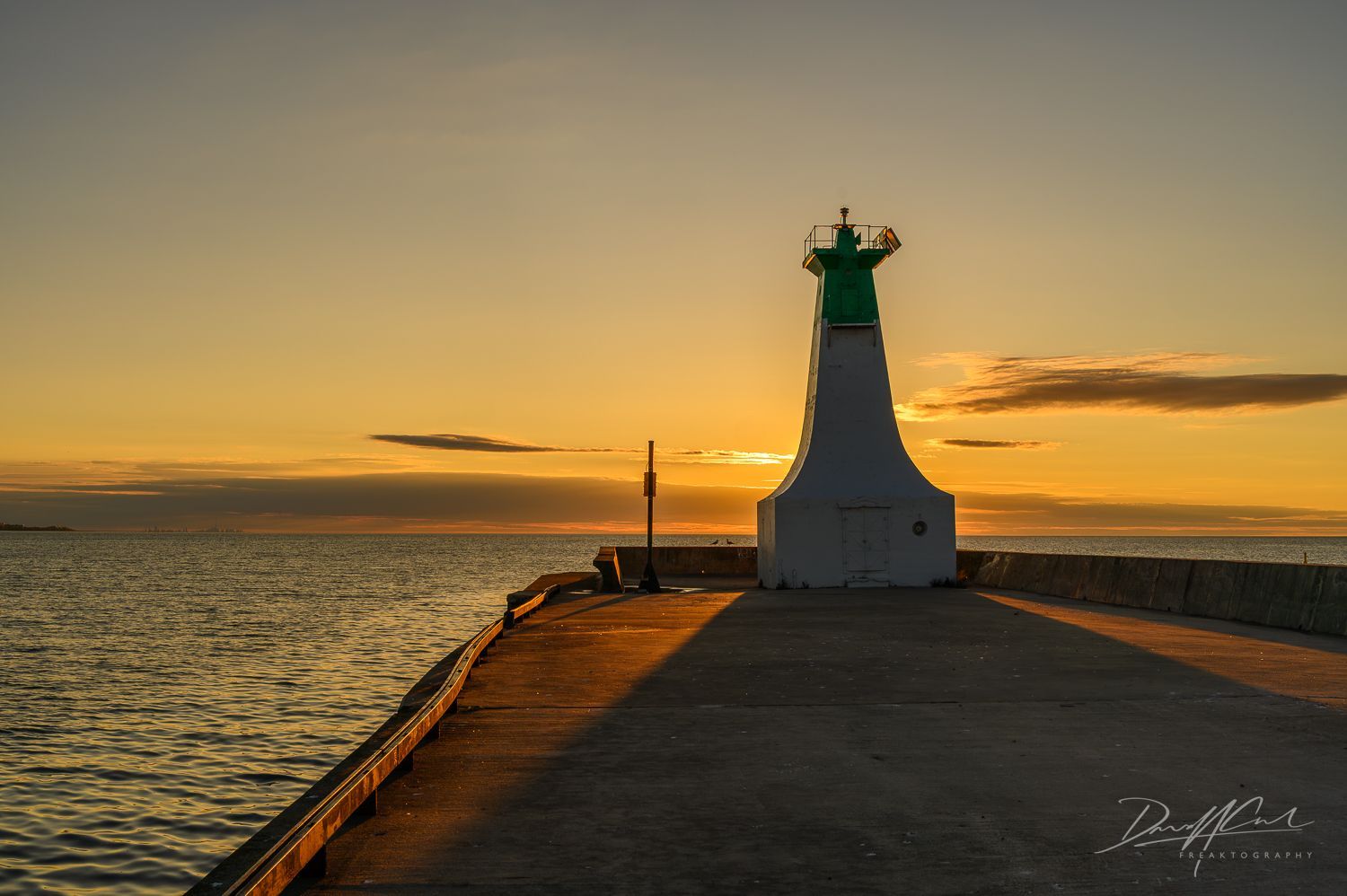 A sunset over a body of water with a lighthouse in the foreground