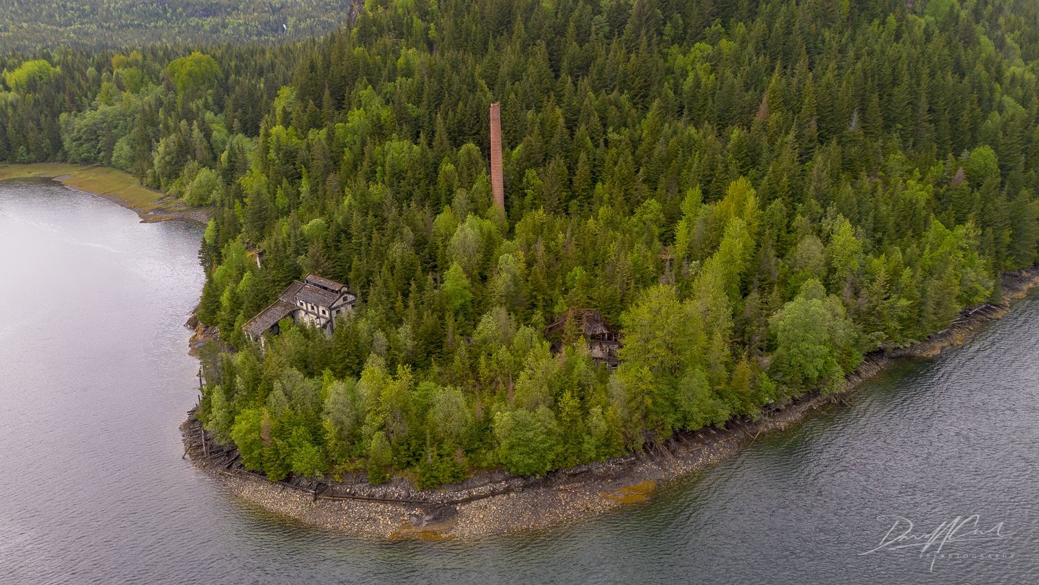 An aerial view of a small island in the middle of a lake surrounded by trees.
