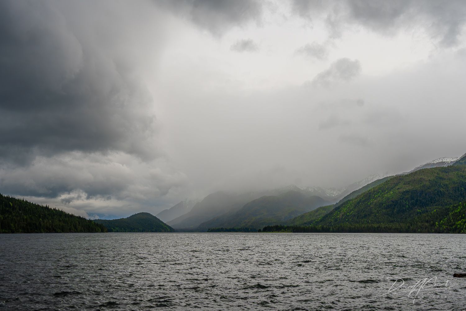 A lake with mountains in the background and clouds in the sky
