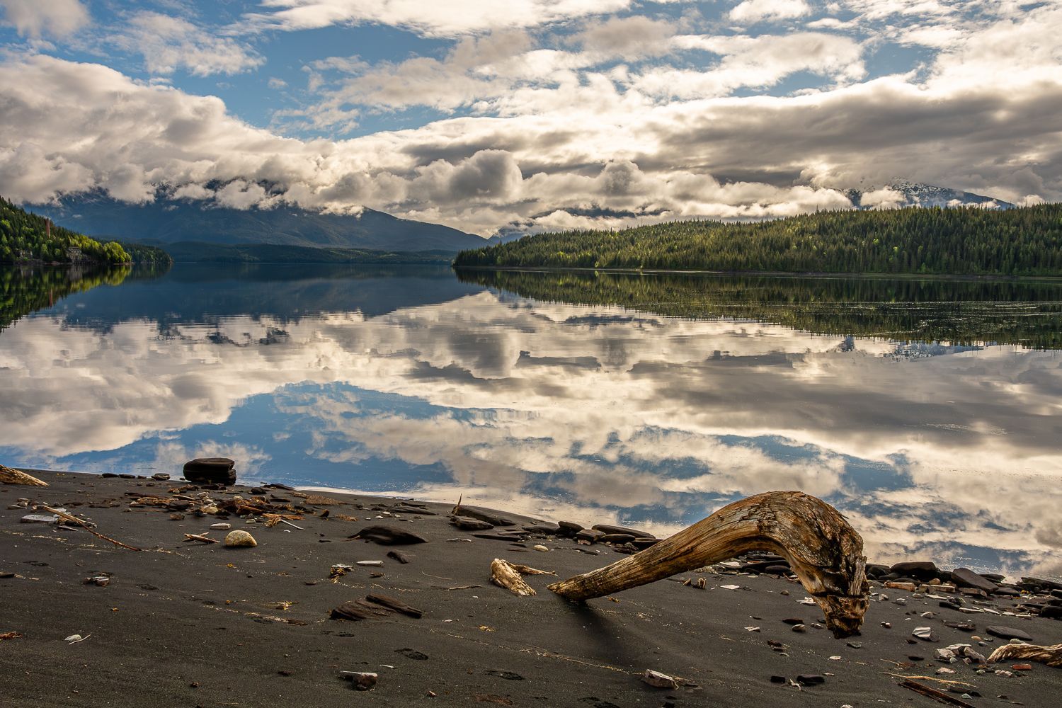 A large body of water with mountains in the background is reflected in the water.