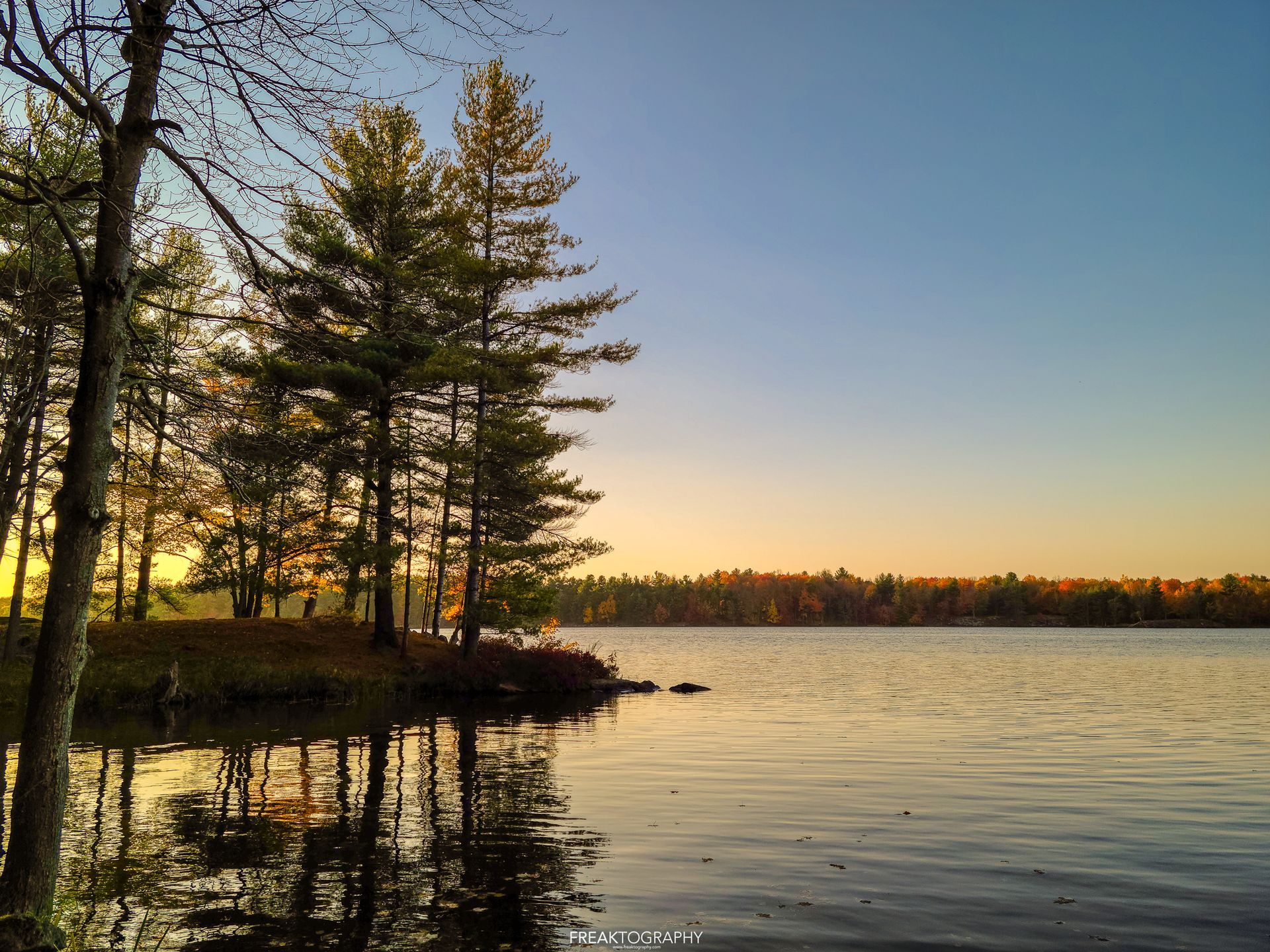 A sunset over a lake with trees in the foreground