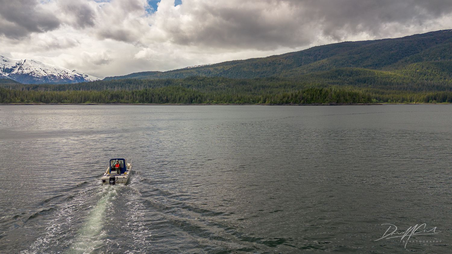 A boat is floating on a lake with mountains in the background.