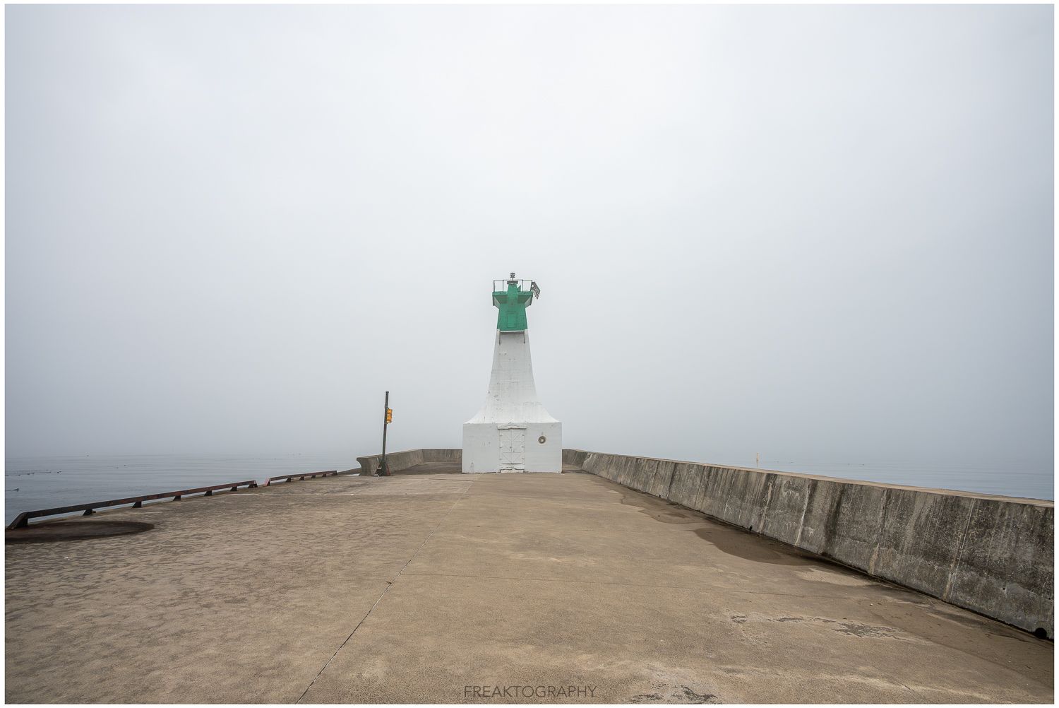 A foggy day with a green lighthouse in the distance