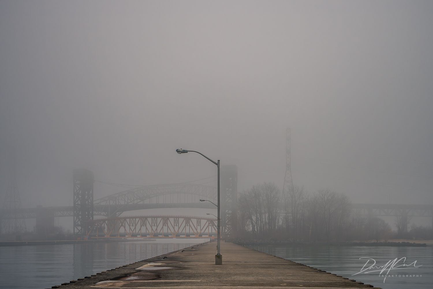 A bridge over a body of water on a foggy day.