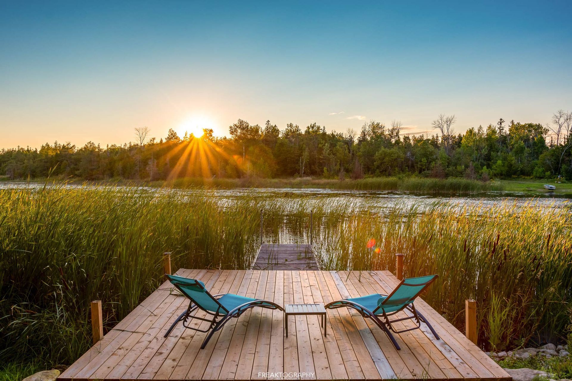 Two chairs are sitting on a wooden deck overlooking a lake.