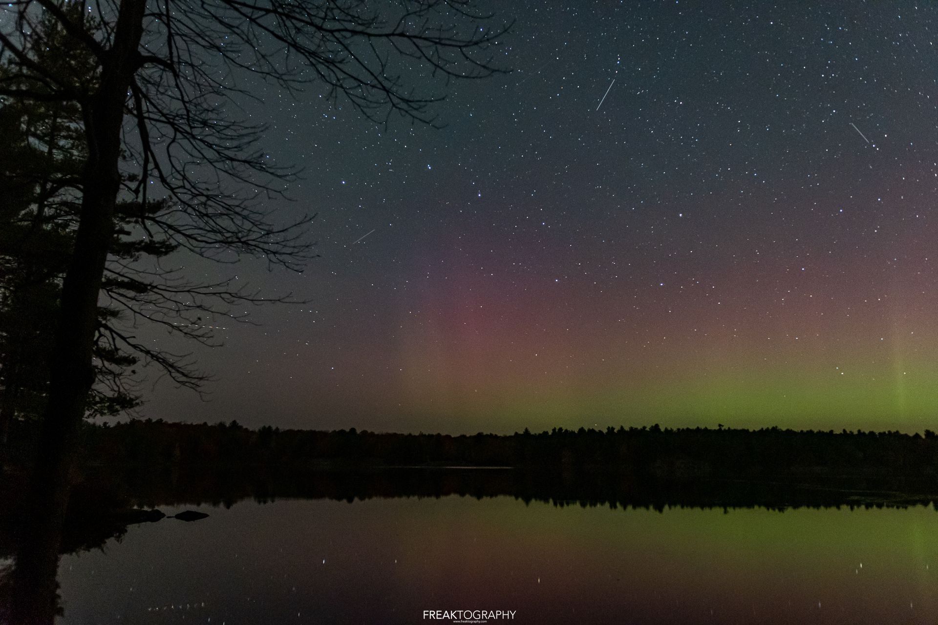 The aurora borealis is visible over a lake at night.
