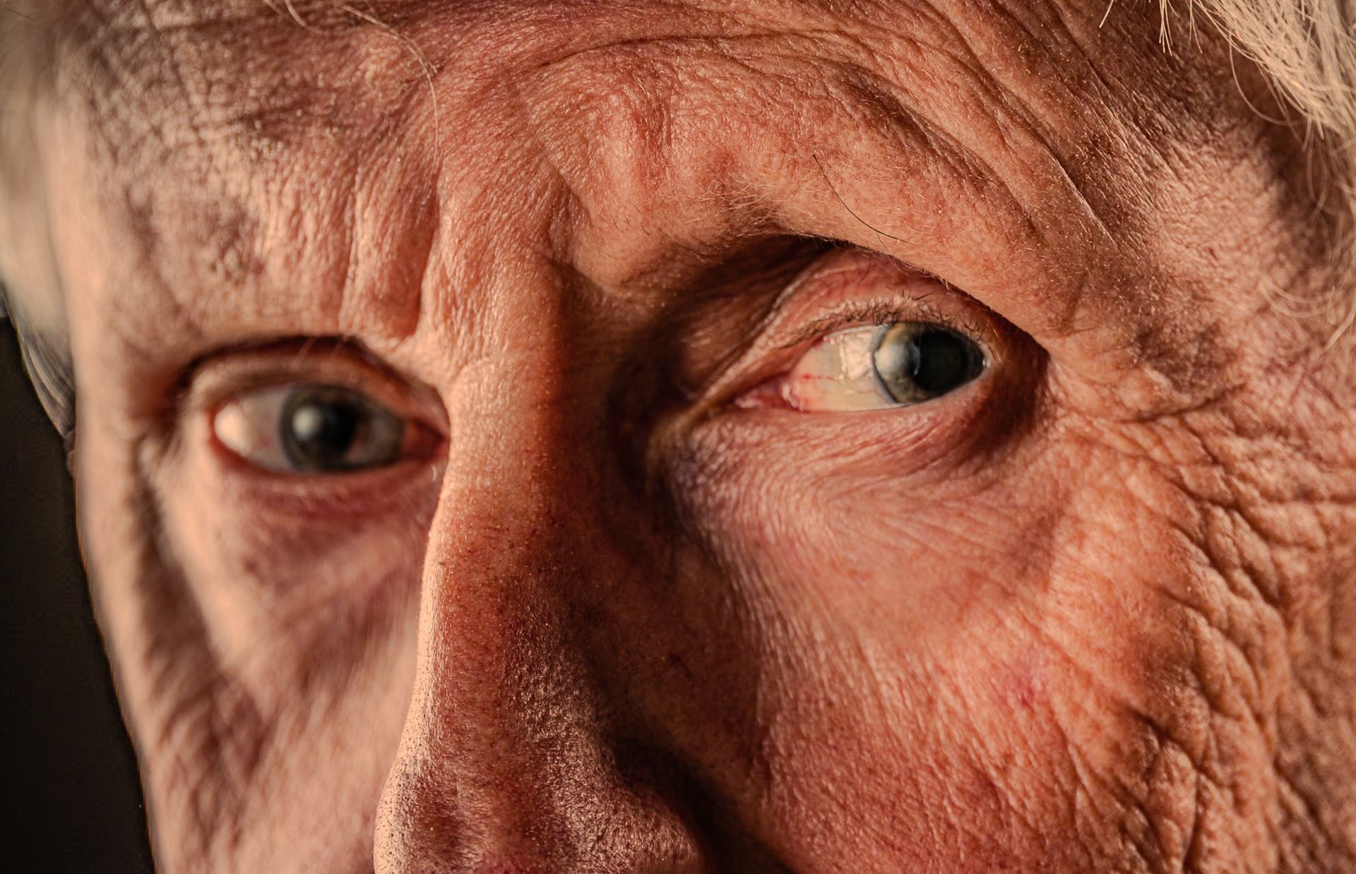 Close-up of an elderly face with deep wrinkles and intense sideways gaze