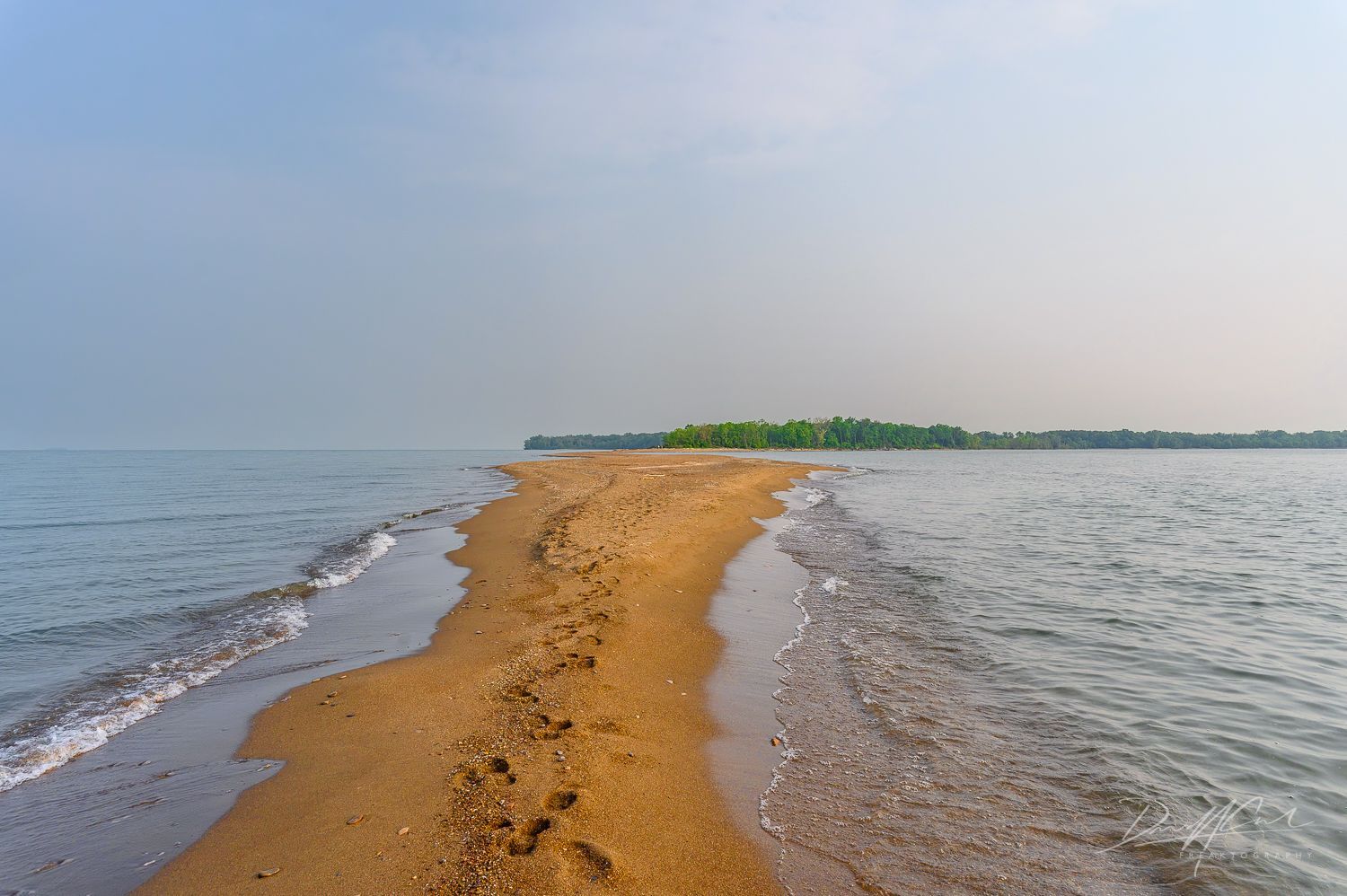 A sandy beach with a small island in the distance.