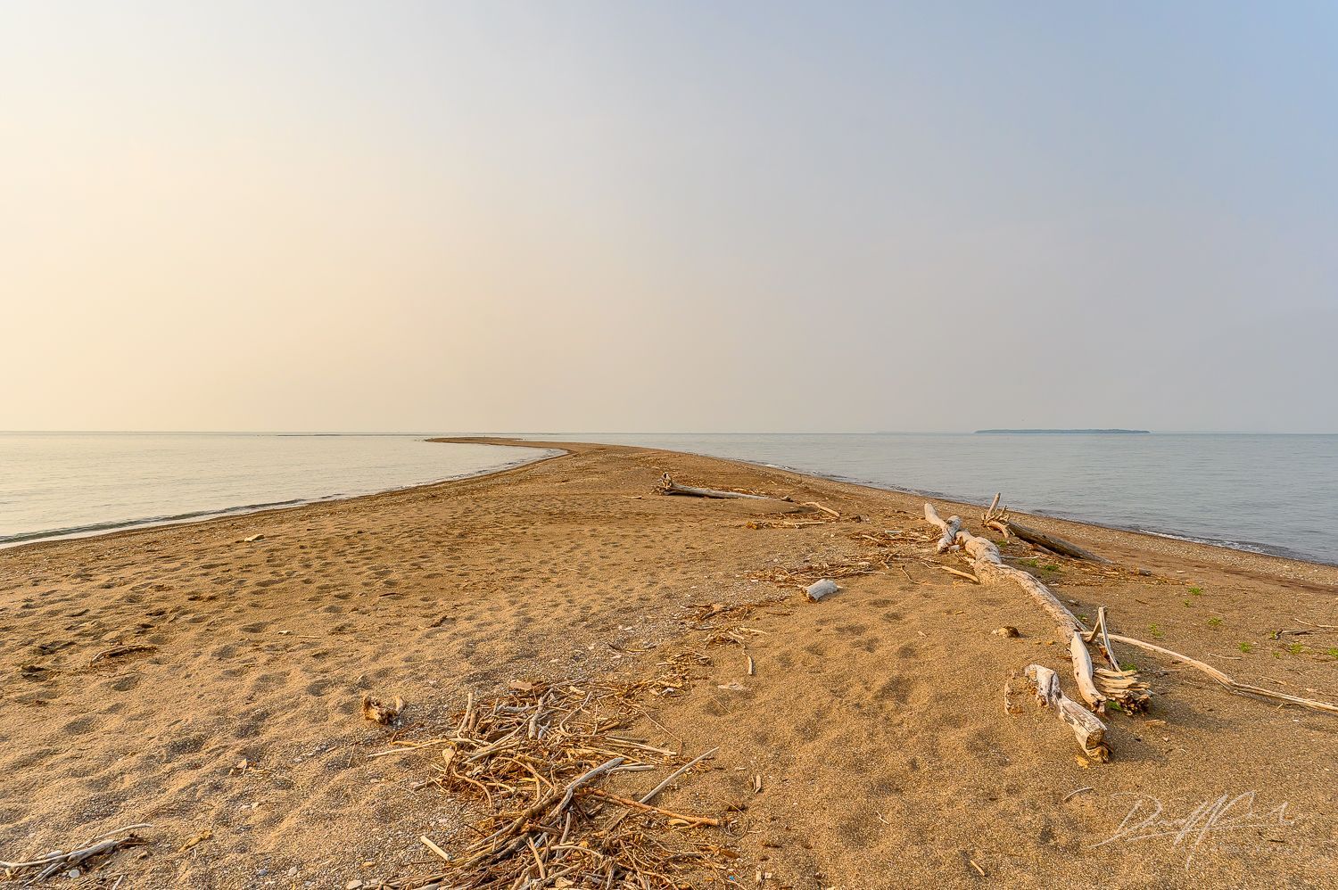 A sandy beach with a large body of water in the background.