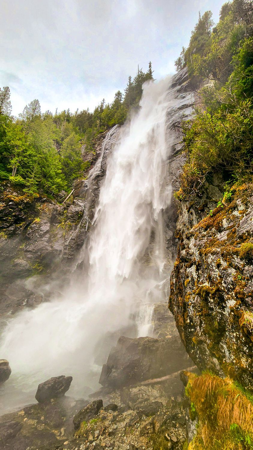 A waterfall is surrounded by trees and rocks in the middle of a forest.