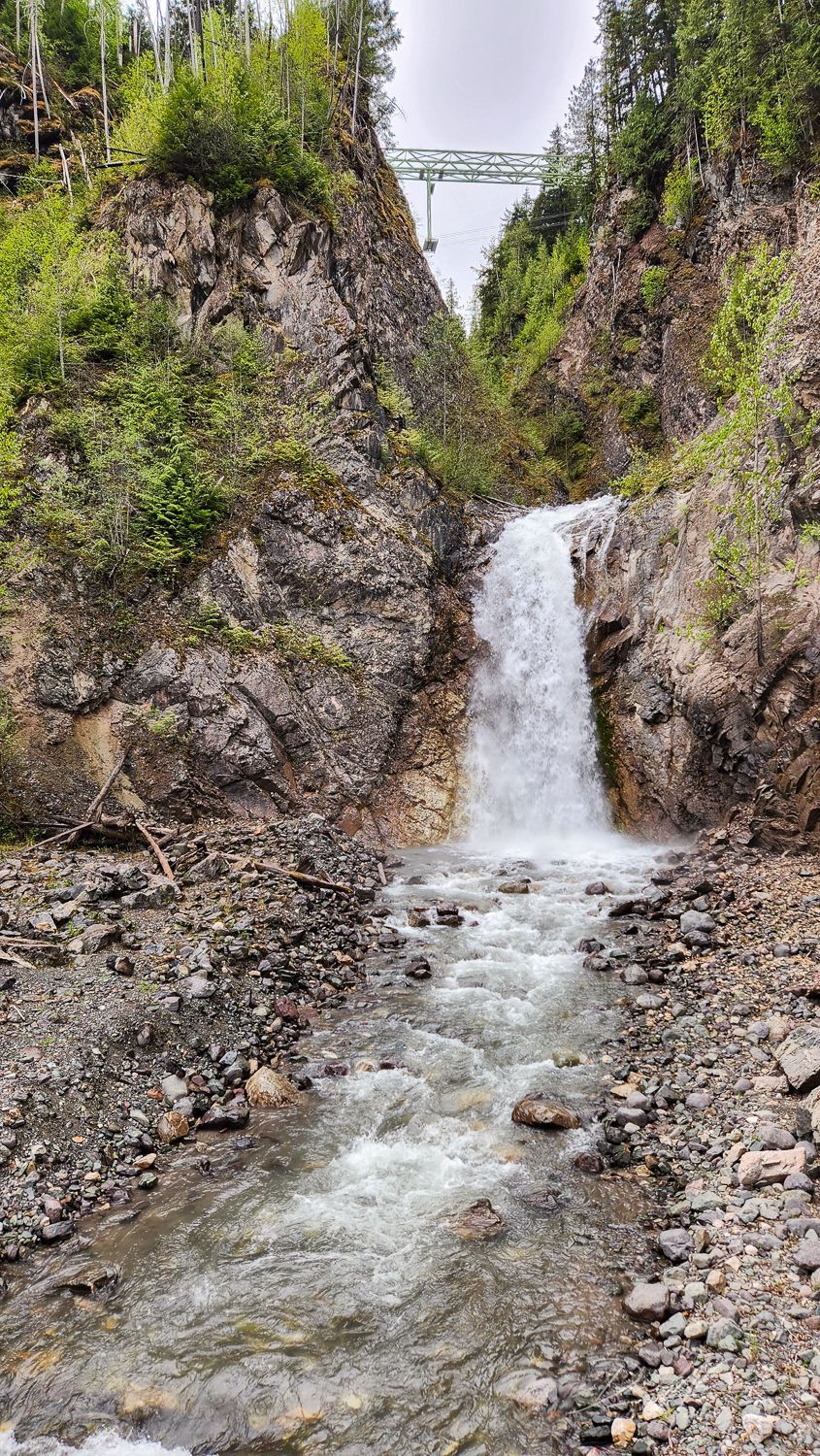 A waterfall is surrounded by rocks and trees in the mountains.