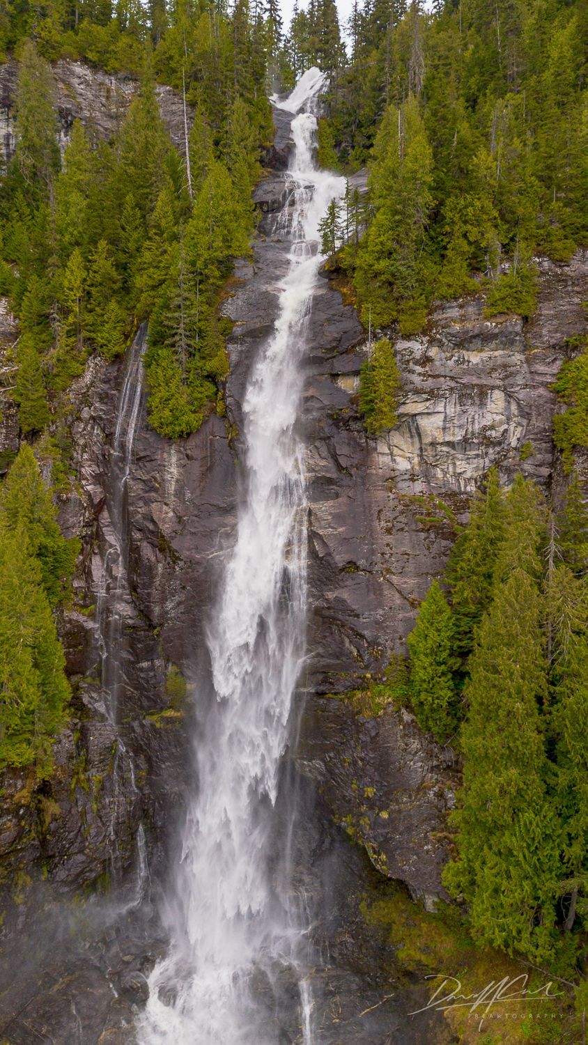 An aerial view of a waterfall in the middle of a forest.