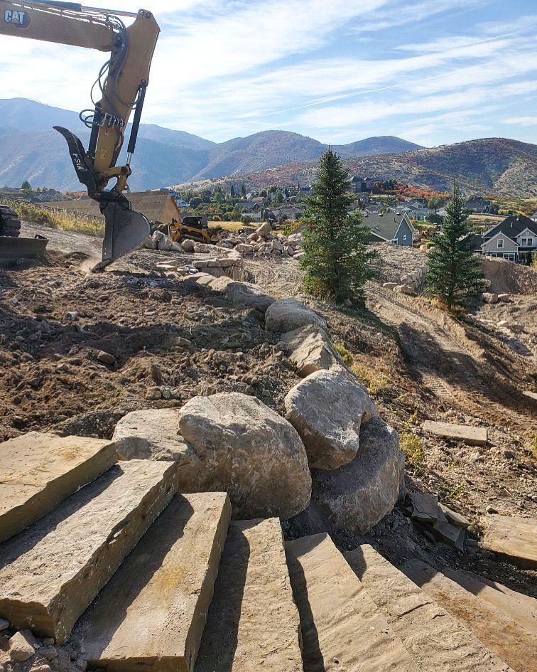 A bulldozer is moving rocks on a construction site with mountains in the background.