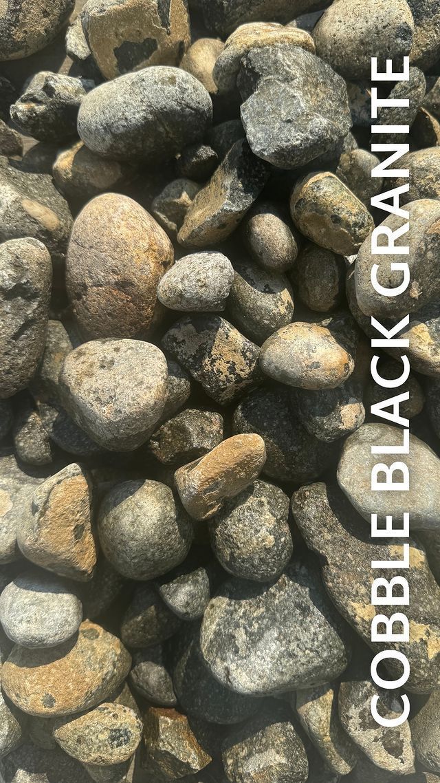 A pile of cobble black granite rocks sitting on top of each other.