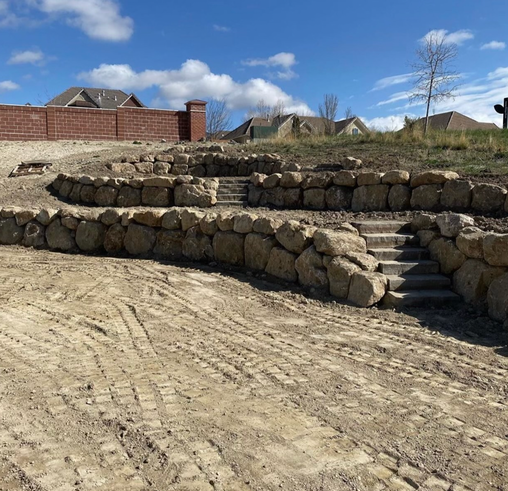A dirt road with a stone wall and stairs