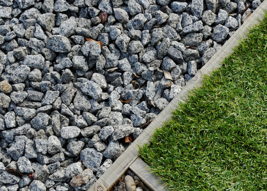 A pile of gravel next to a patch of grass.