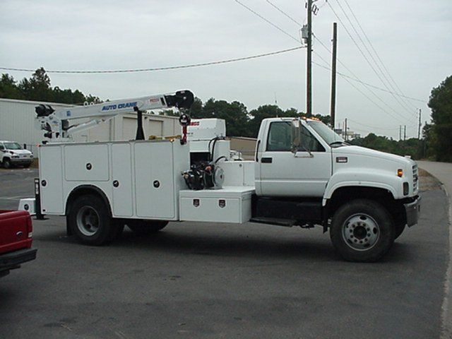 A white service truck is parked on the side of the road