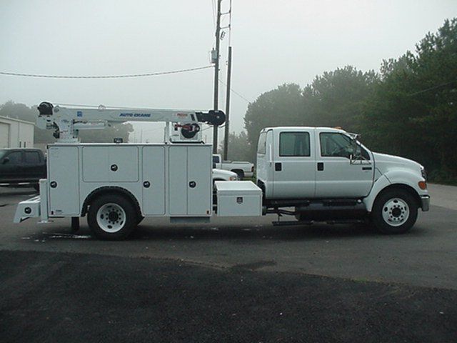 A white utility truck with a crane on top of it