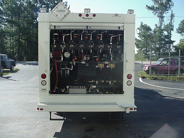 A white truck is parked in a parking lot with the back door open