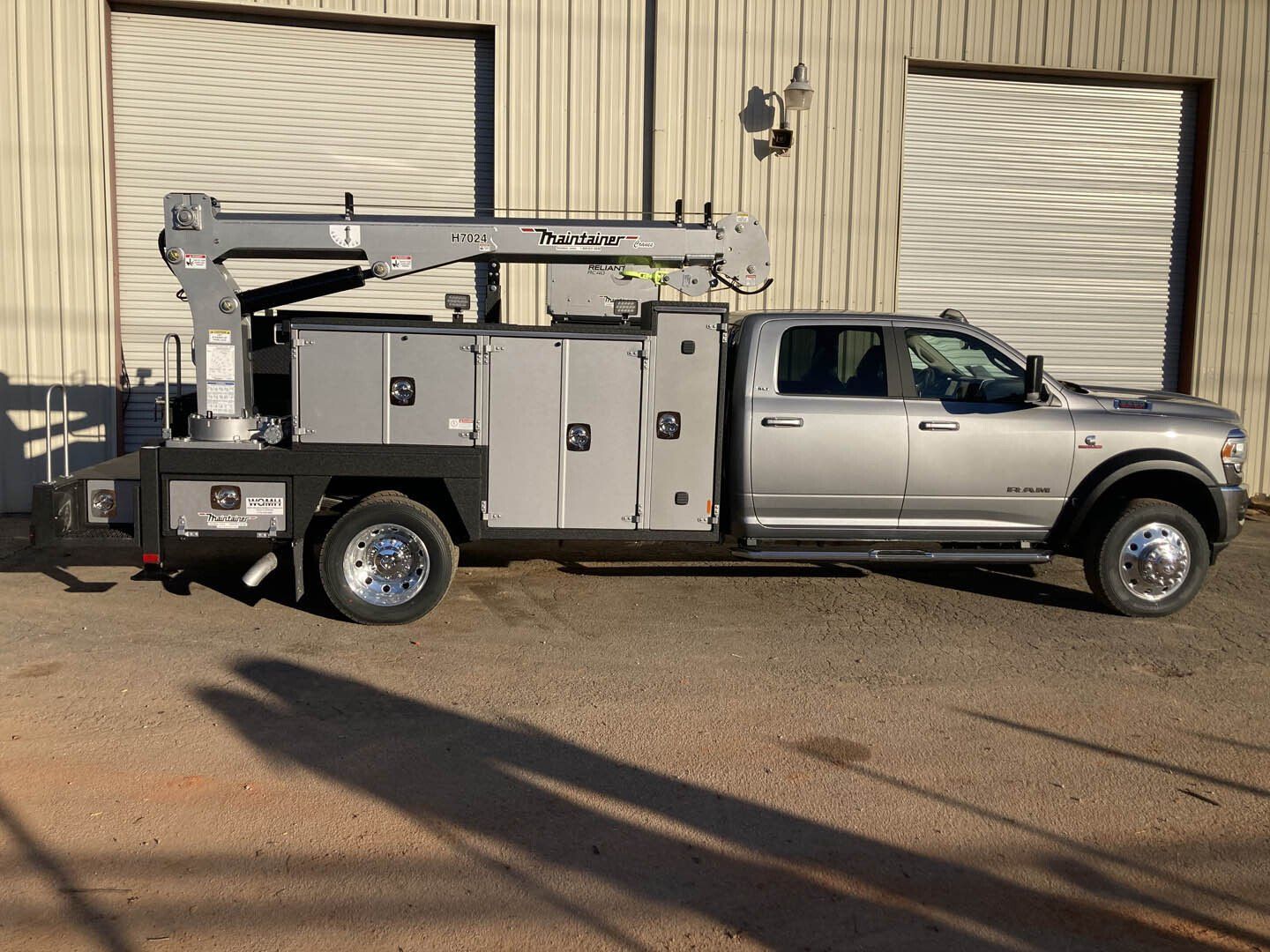 A utility truck with a crane attached to it is parked in front of a building.
