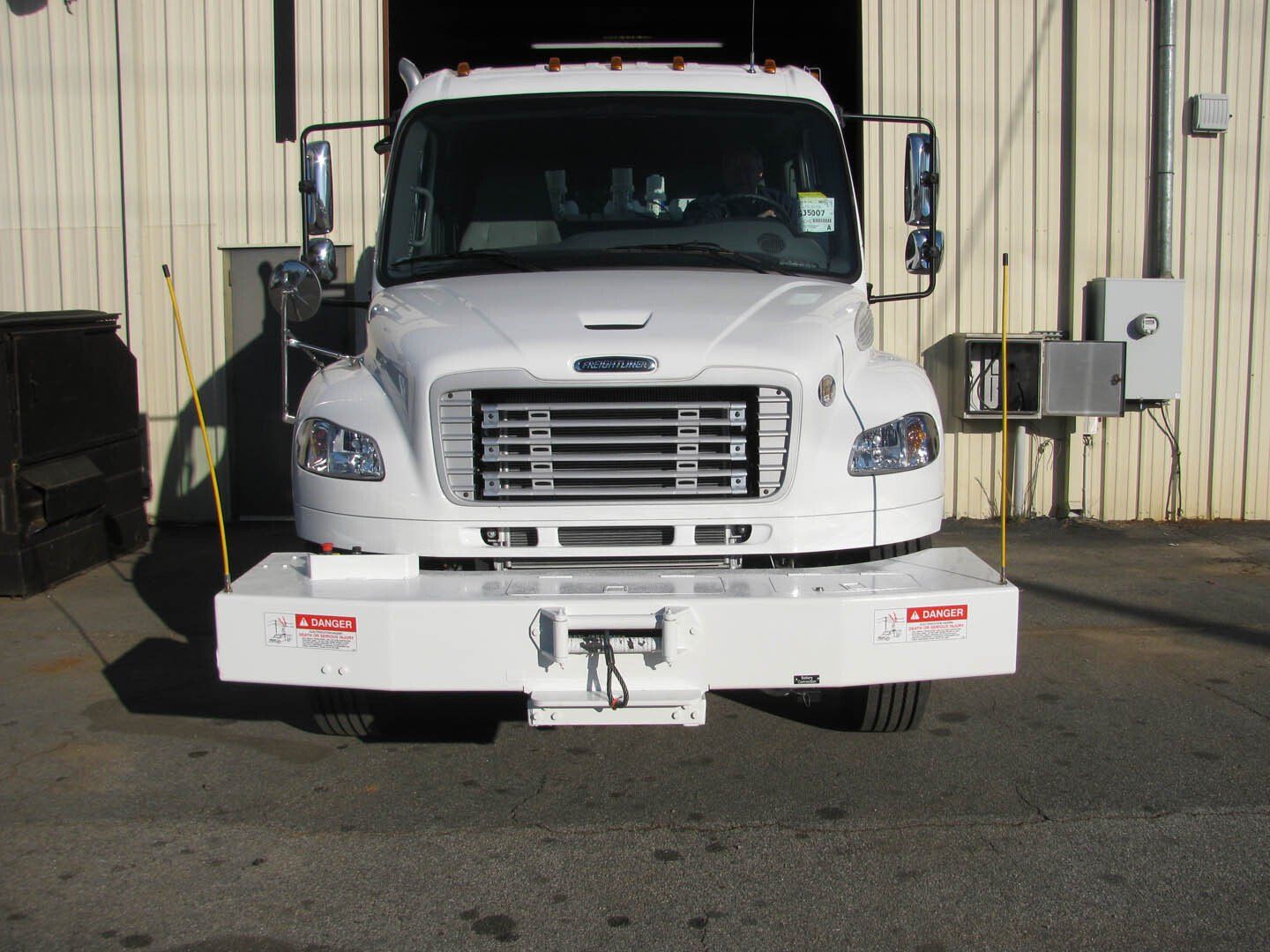 A white truck is parked in front of a building
