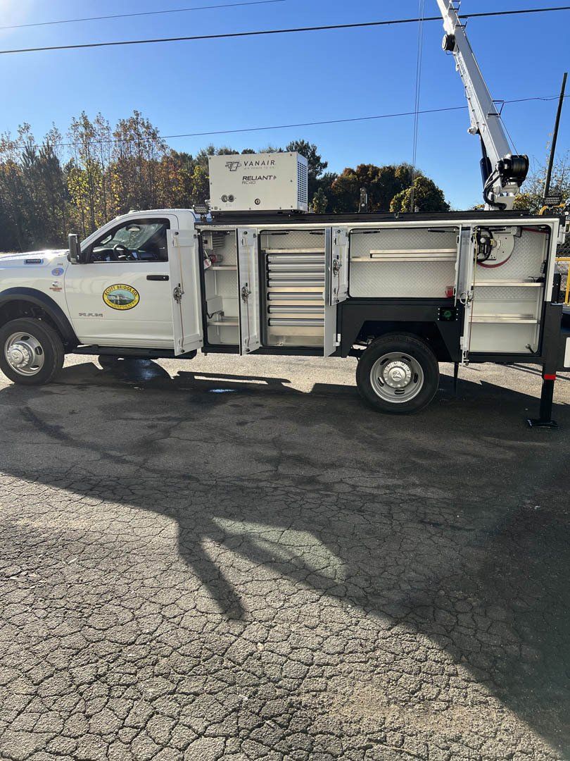A white truck with a crane on the back is parked in a parking lot.