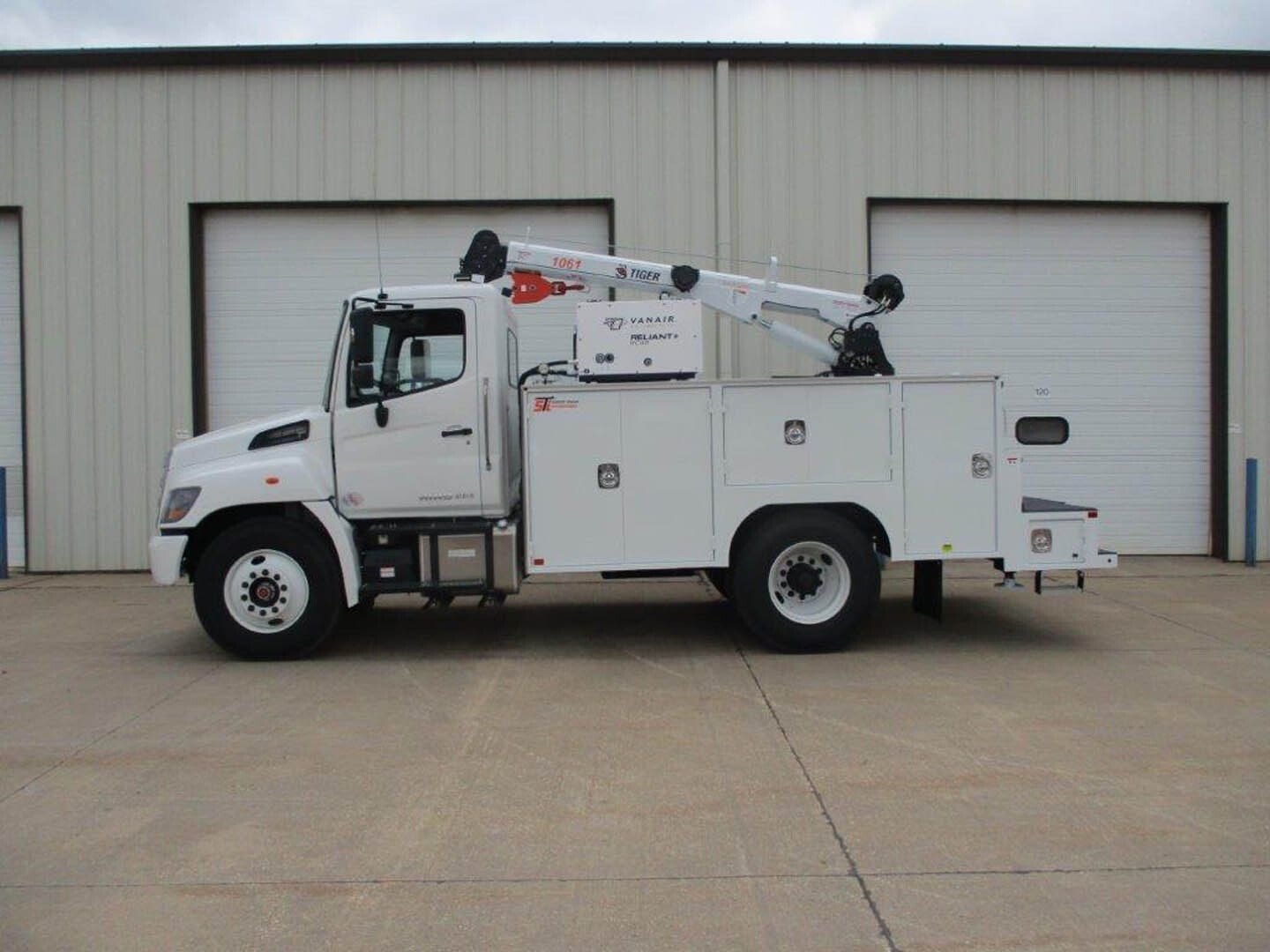 A white utility truck is parked in front of a building.